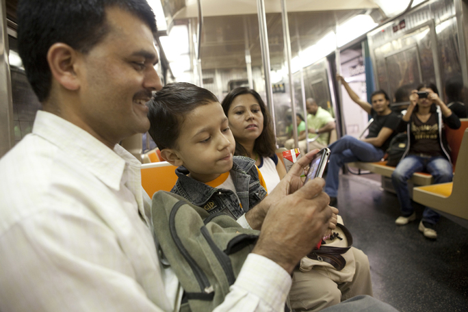 The Timsina family looking at photographs on a cell phone while riding a subway in New York. IRC/MCohen