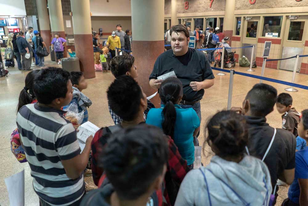 An IRC community engagement coordinator helping a group of refugees learn about travel and the airport. IRC/Andrew Oberstadt