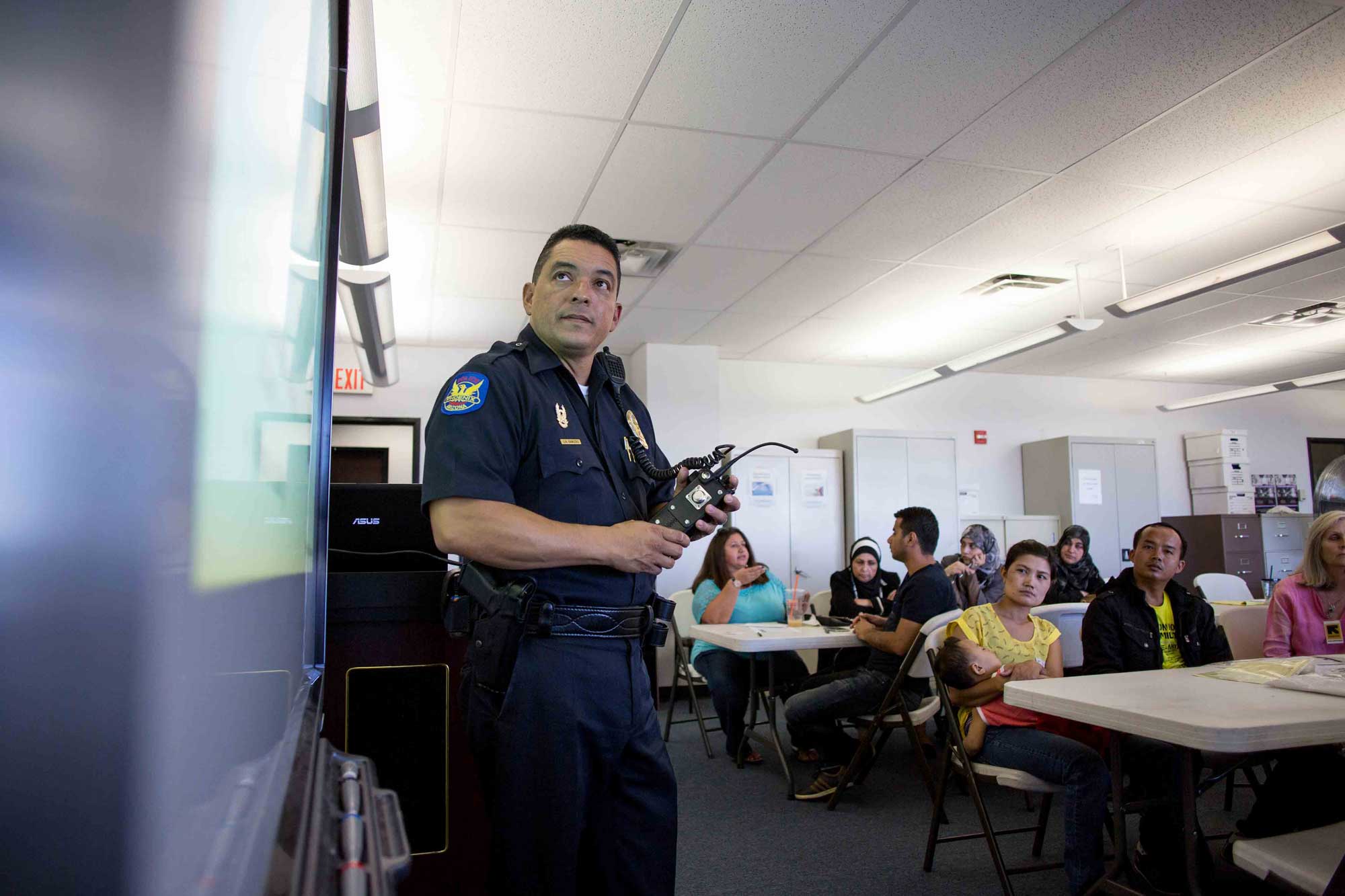 A police officer speaking to refugees about community services during a cultural orientation class