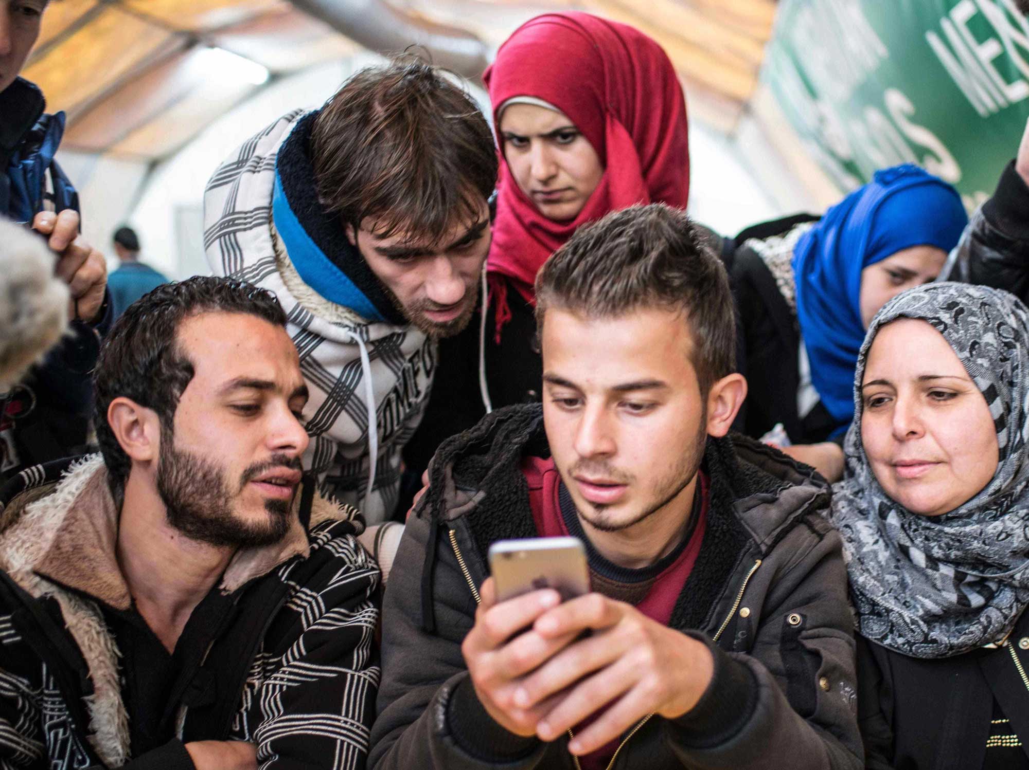 A Syrian refugee family looks at resources on a cell phone