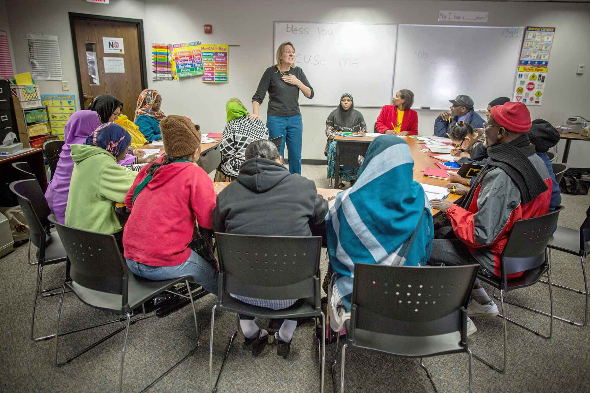 A cultural orientation trainer teaching a class of recently resettled refugees about U.S. cultural norms