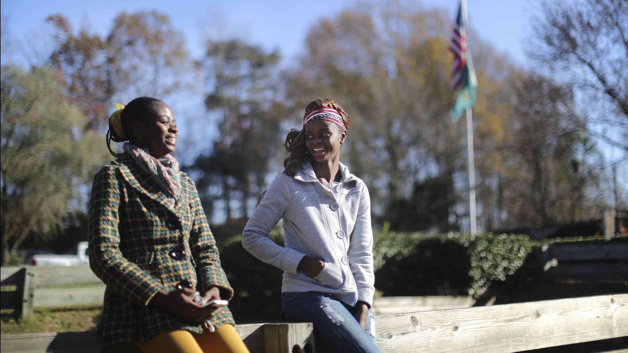 Two refugee sisters talking together outside their home