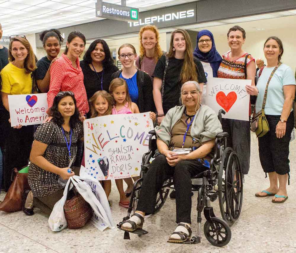 A group of refugee resettlement staff workers greeting a refugee family at the airport