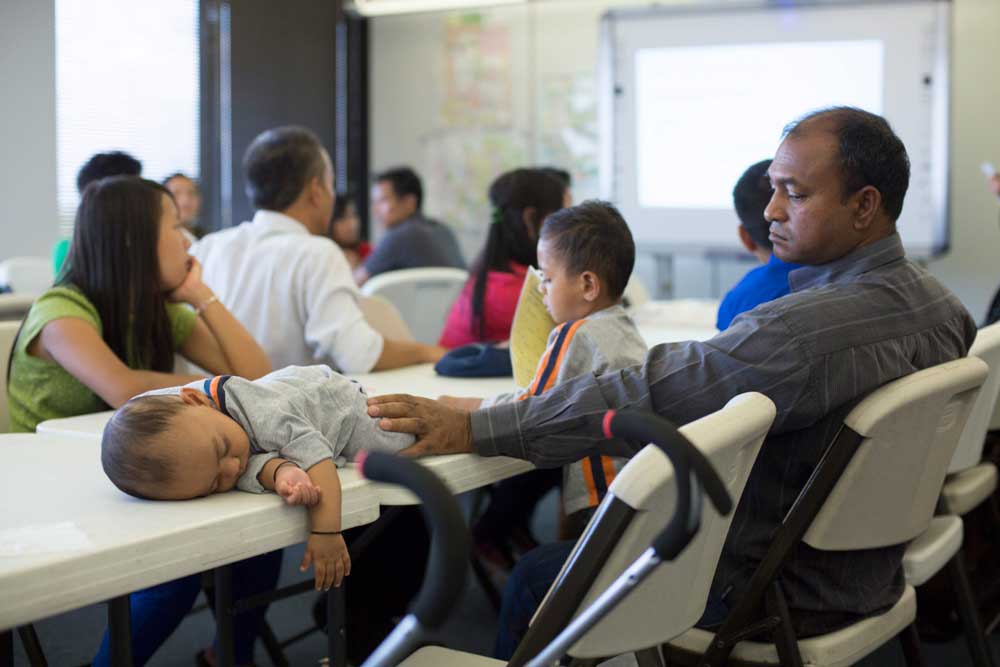 A refugee father keeps his child safe as he listens to a cultural orientation lecture at the IRC office in Phoenix.