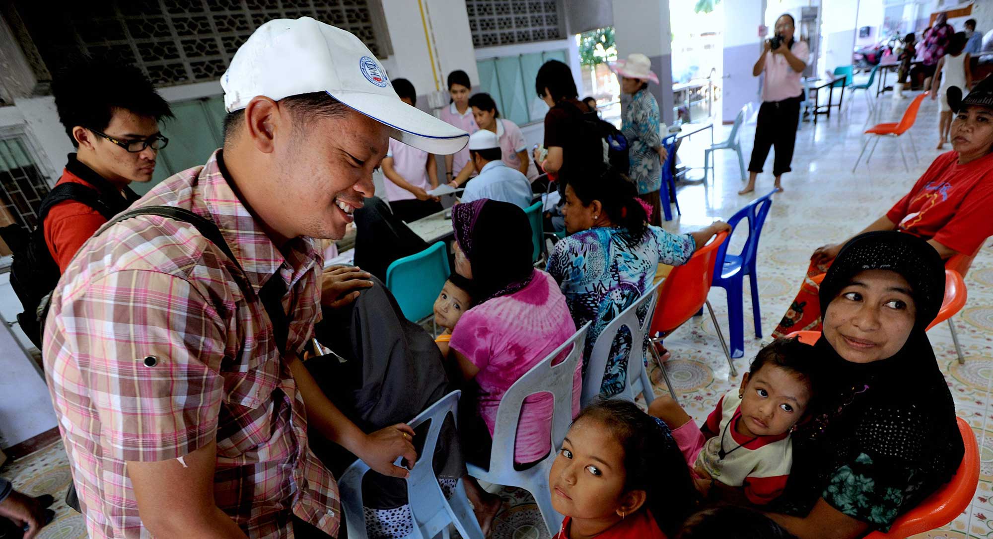 An IRC migrant health volunteer helps a Burmese family with translation