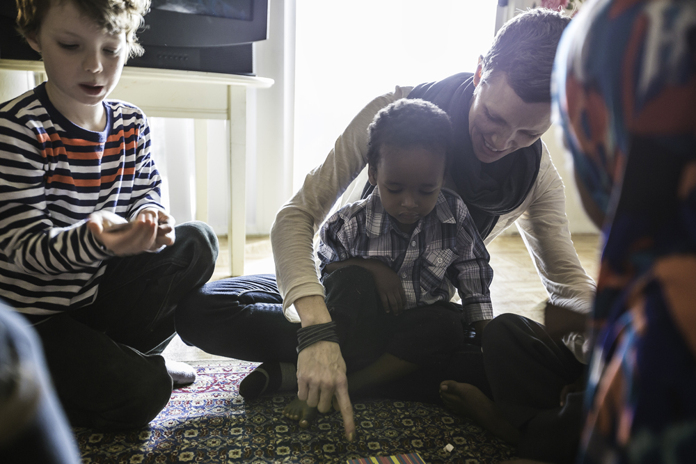 A refugee resettlement caseworker helping a group of young refugee children during class