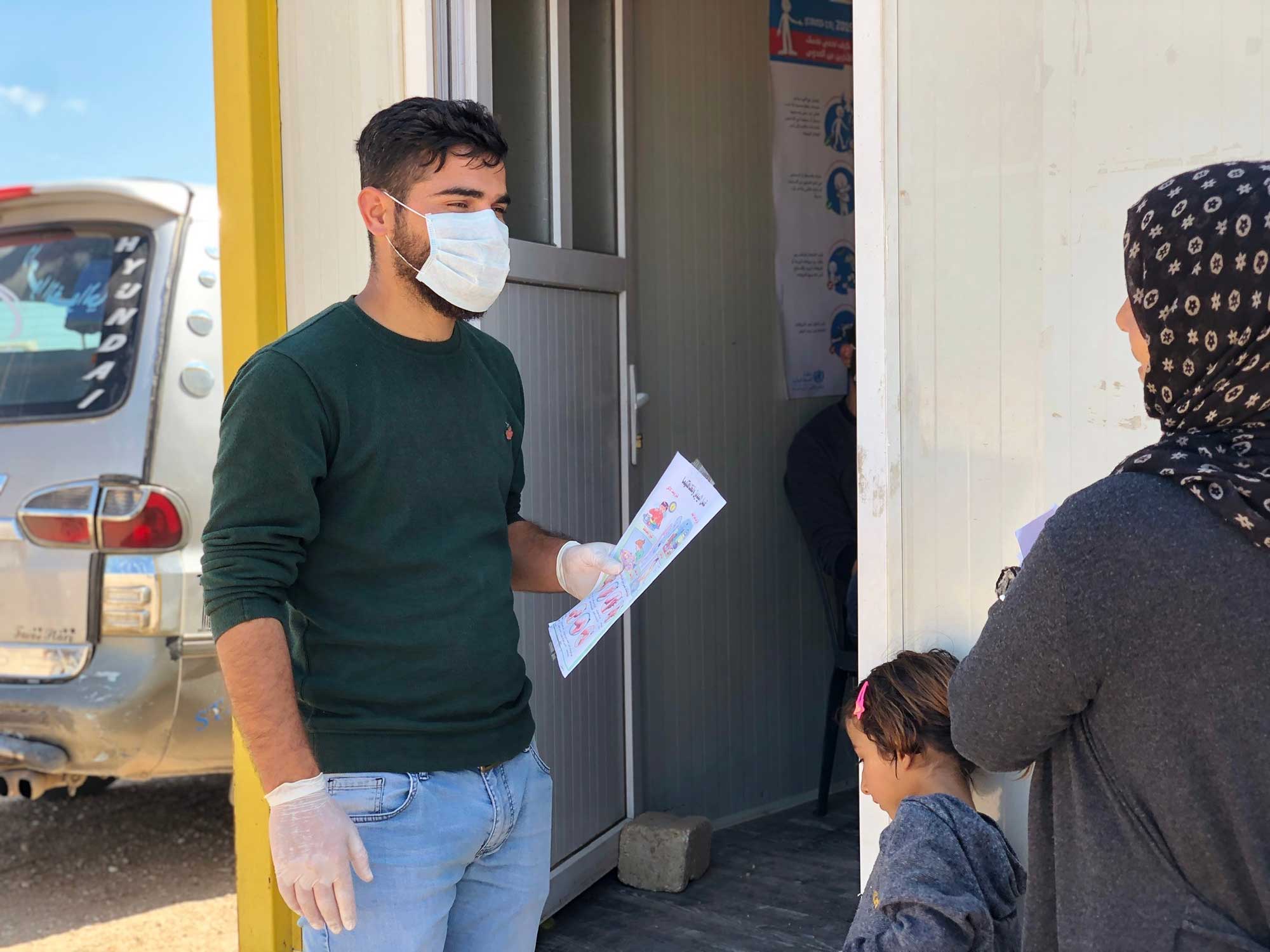 A health worker raises the awareness of patients waiting for their appointments outside a primary health care clinic. Photo/IRC