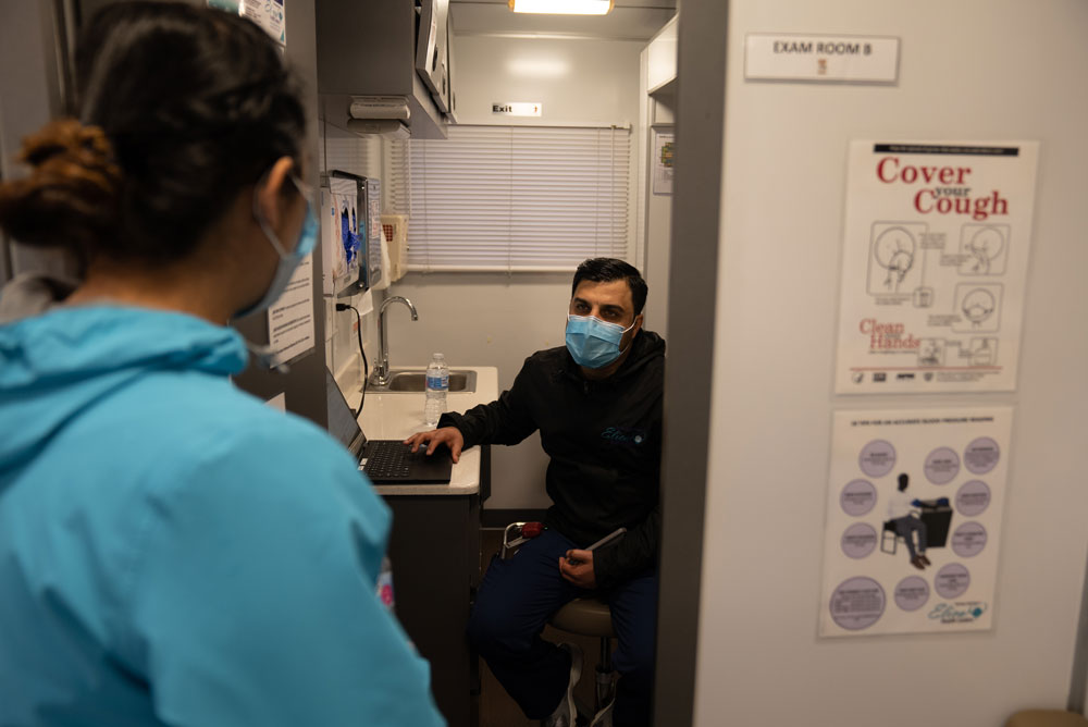 Two mobile health clinic workers talking. They are both wearing masks due to COVID-19. IRC/DKnowles