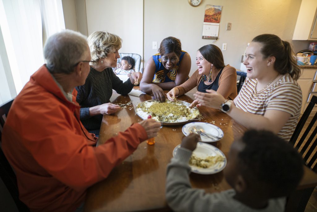 Jacqueline (center) shares a Congolese meal with her friends, Chris Johnson, 65, Jenny Hirst, 55, Janna Brown, 29, and Charlie, 16. Jacqueline Uwumeremyi, 43, fled the Democratic Republic of Congo to South Africa in 1998 because of escalating violence. In South Africa, Jacqueline faced constant xenophobia and feared for her and her family's safety.